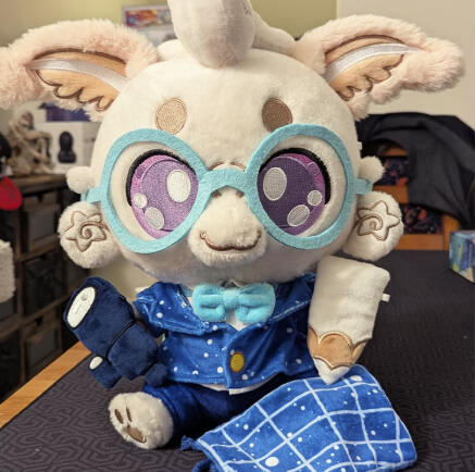 Laisy Luna Moth Plushpanion Laisy Luna Moth Plushpanion: A white mothy plush sits on a black mat. The white fluffy moth is wearing light blue glasses, a star (white dot) cobalt blue blazer, with matching navy blue trousers. They're holding a white pencil and dark blue telescope prop.
